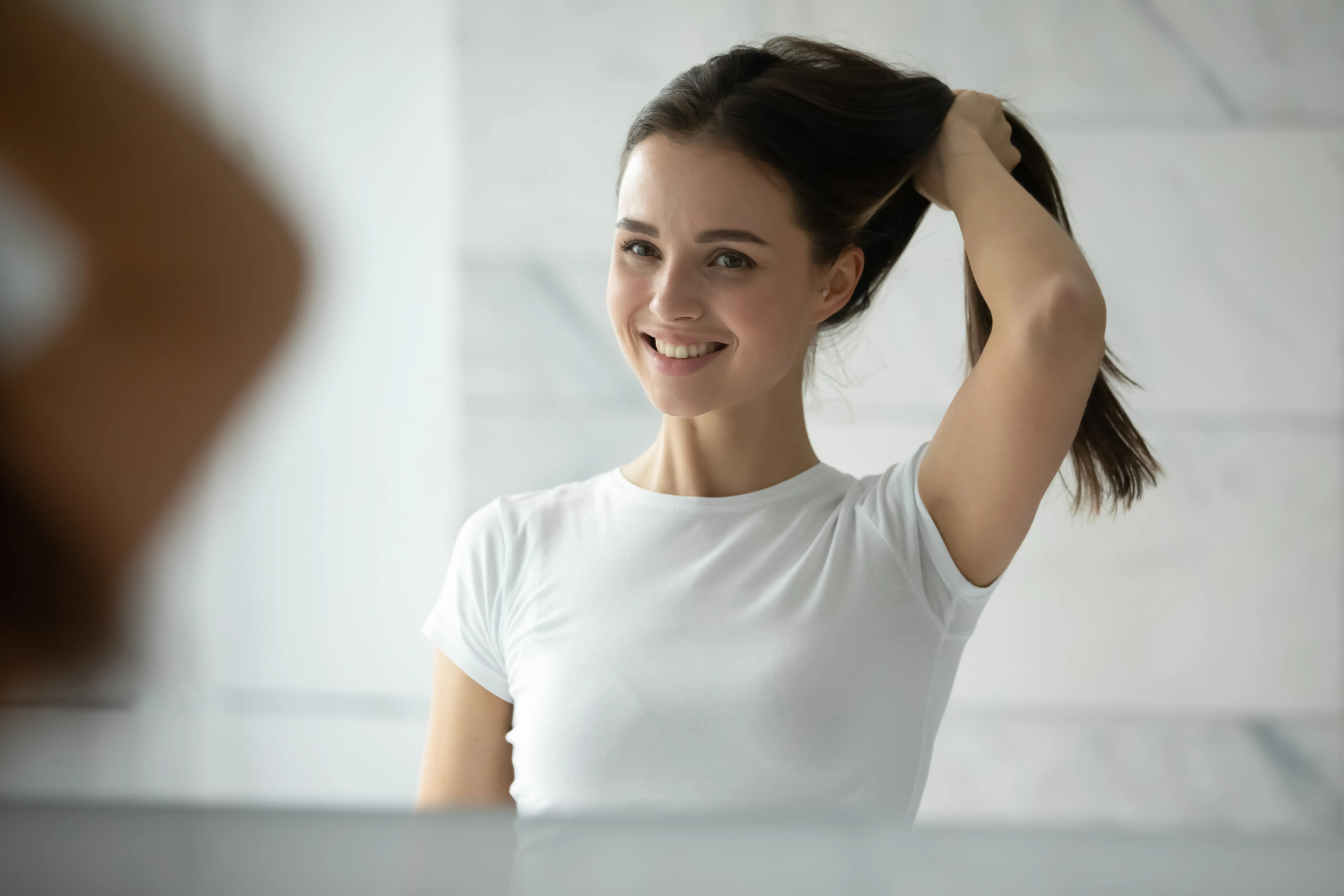 woman looking mirror holding hair