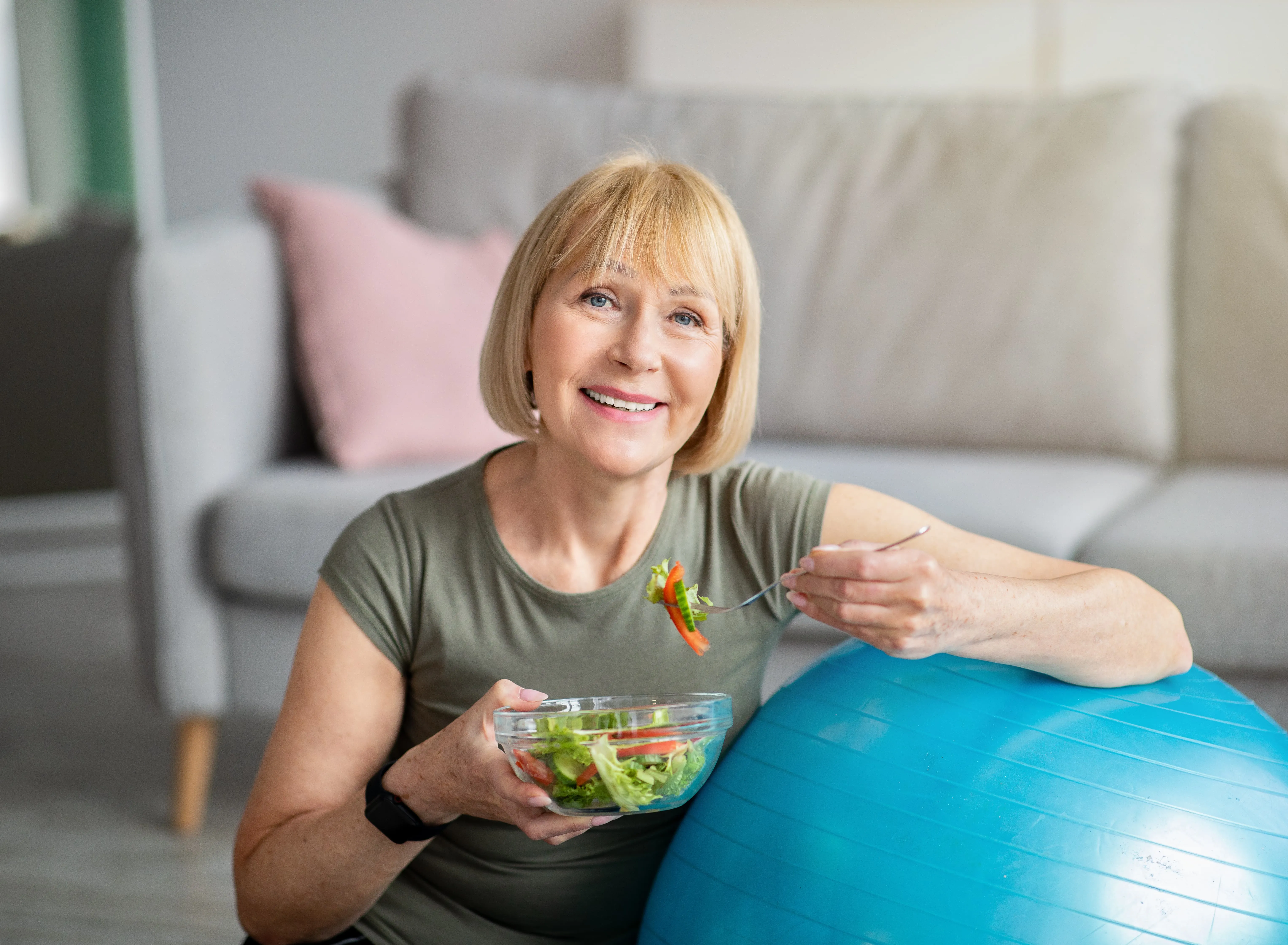 woman eating salad leaning on yoga ball